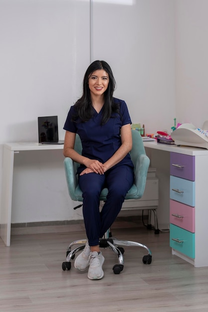 Attractive doctor sitting in her office desk chair looking into the camera