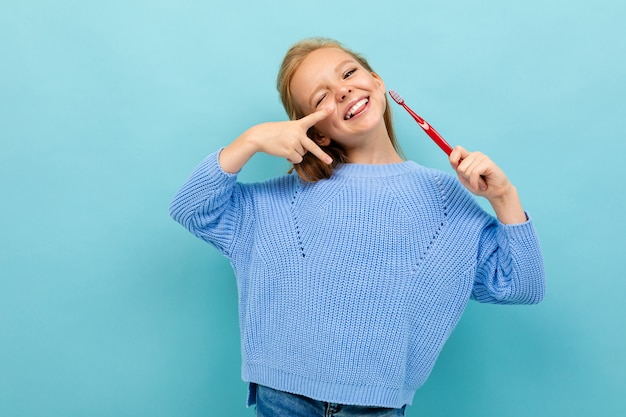 Attractive european girl holding a toothbrush in her hands on light blue wall