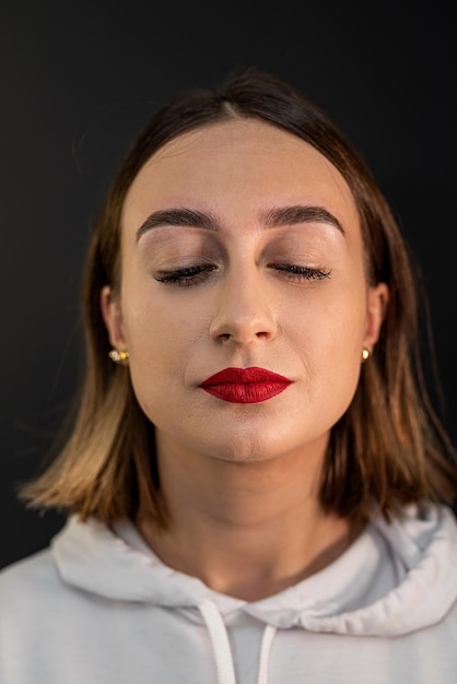 Attractive fashionable young lady with mysterious brown eyes flowing hair and red lips posing