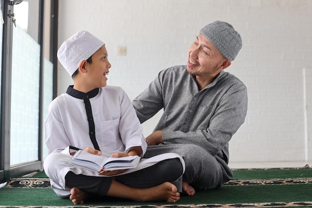 Attractive father and son having bonding moments while teaching and learning Quran at the mosque