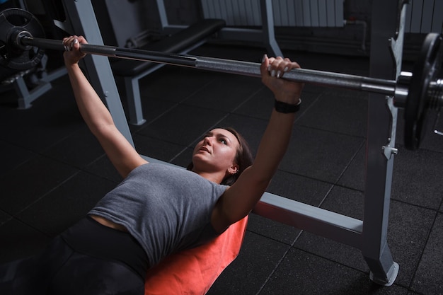 Attractive female athlete doing bench press at gym