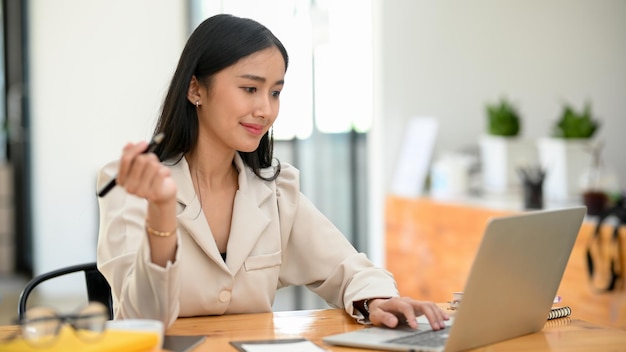 Attractive female boss or business leader working on laptop computer in her modern private office