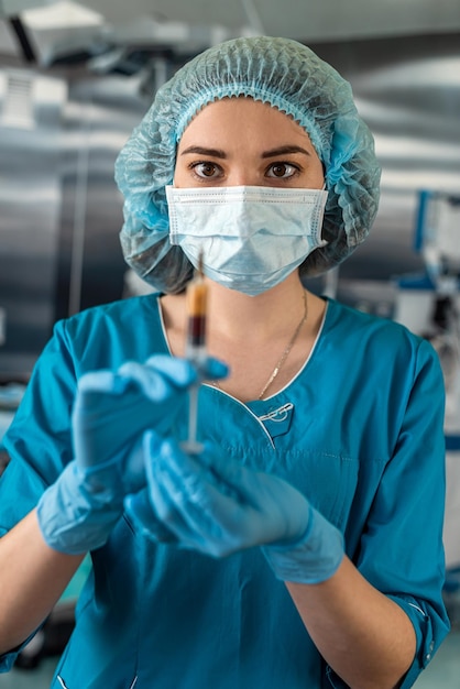 Attractive female doctor holding syringe in operating room for patient