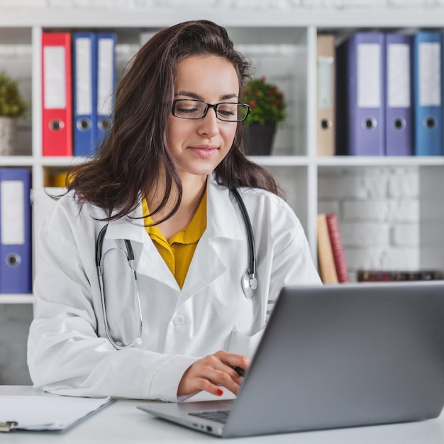 Attractive female doctor working on her laptop in hospital office