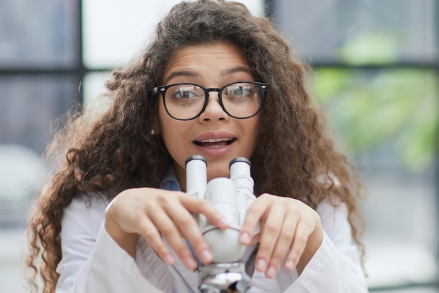 Attractive female scientist looking through a microscope