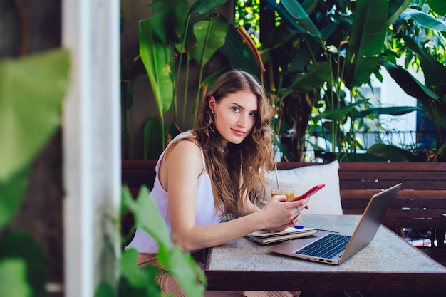 Attractive female using smartphone in summer cafe