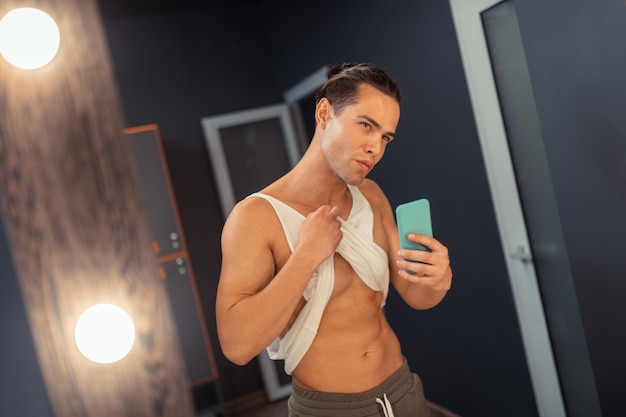 Attractive fit man taking a photo in the mirror