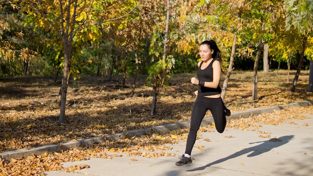 Attractive fit woman athlete running at speed along a rural lane through a park