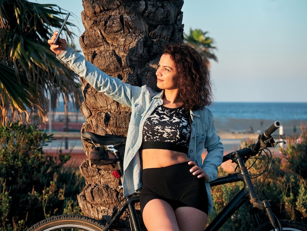 Attractive and fit woman in sportswear, making a selfie while cycling in a park