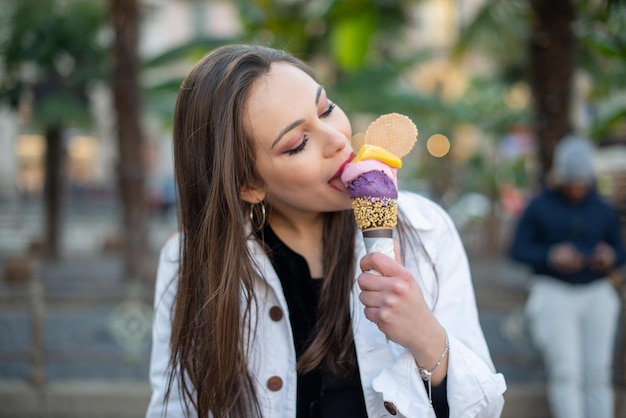 Attractive girl eating ice cream on the city street