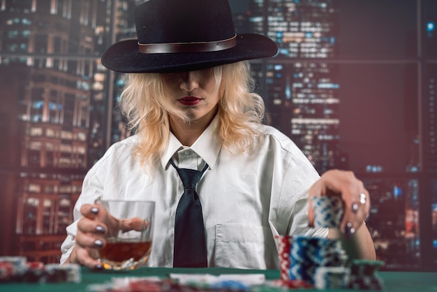 attractive girl holding cards and poker chips at casino table hiding her gaze