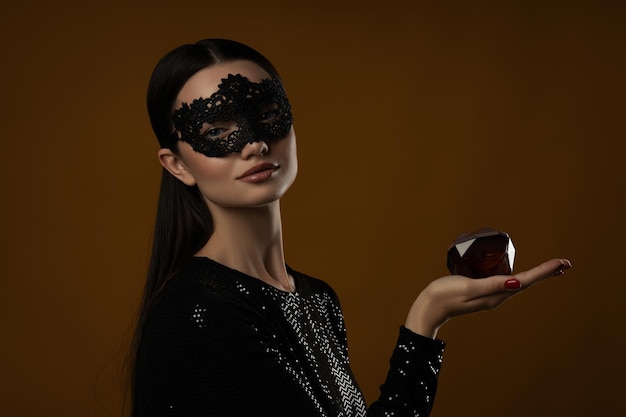 Attractive girl in a mask with perfume in her hand