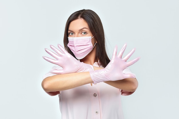 An attractive girl in pink gloves and a protective mask