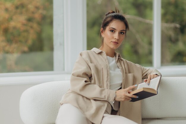 Attractive girl reading book on sofa at home