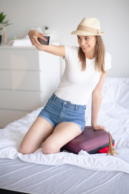 Attractive girl sitting on sofa and packing luggage