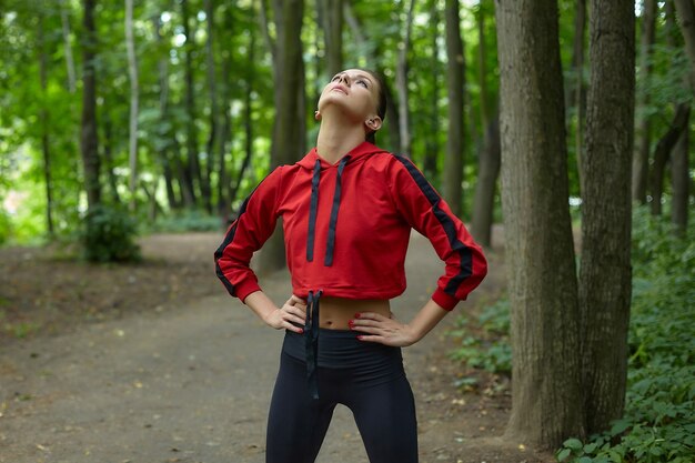 Photo attractive girl in sportswear is doing gymnastic exercises on the track in the forest park.