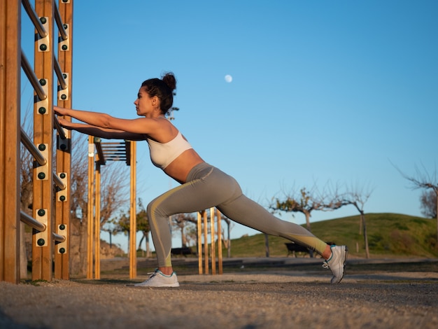 Attractive girl stretching in an outdoor park at sunset.