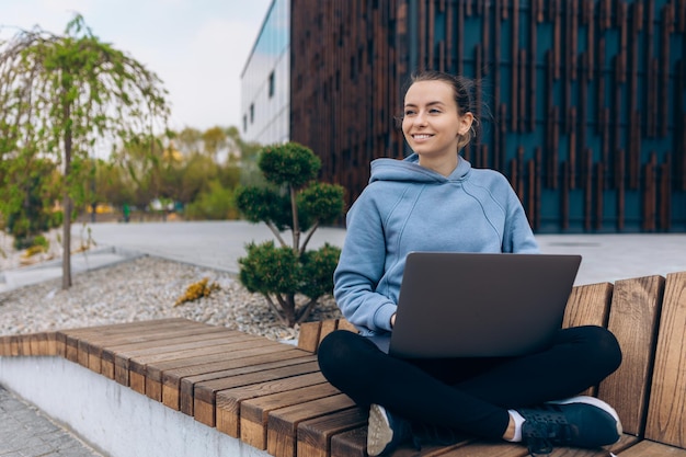 Attractive girl with ponytail sitting with crossed legs on bench