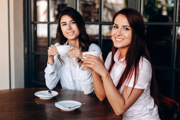 Attractive girls posing in cafe, drinking sweet coffee. Workflow 