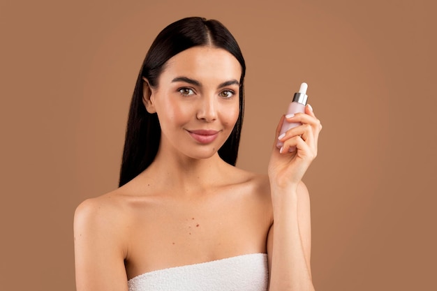 Attractive halfnaked millennial woman holding small pink bottle