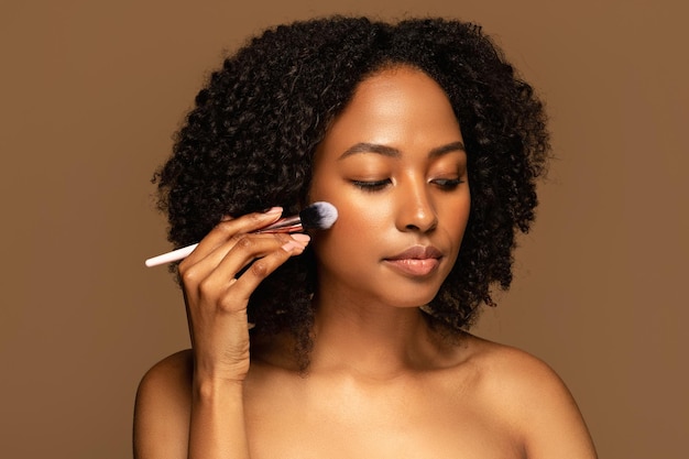 Attractive halfnaked young black woman holding makeup brush