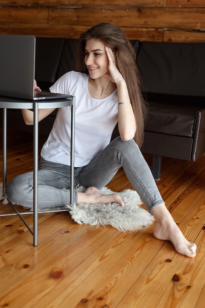 Attractive happy smiling girl student having video chat sitting on the floor