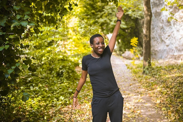 Attractive happy smiling young natural beauty short haired african woman wearing total black walking