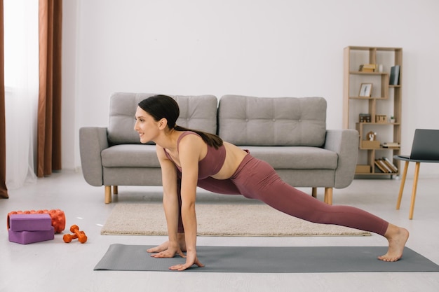 Attractive and healthy young woman doing exercises while resting at home