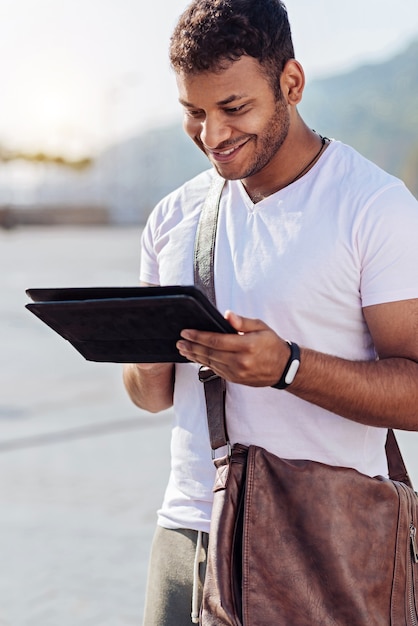 Attractive international student bowing head while using his gadget and keeping smile on his face