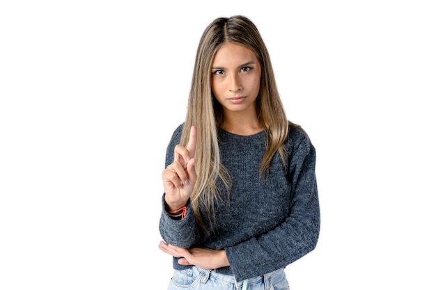 Attractive Latina woman with an angry or serious expression making a NO sign with her index finger on a pure white background. Studio photography.