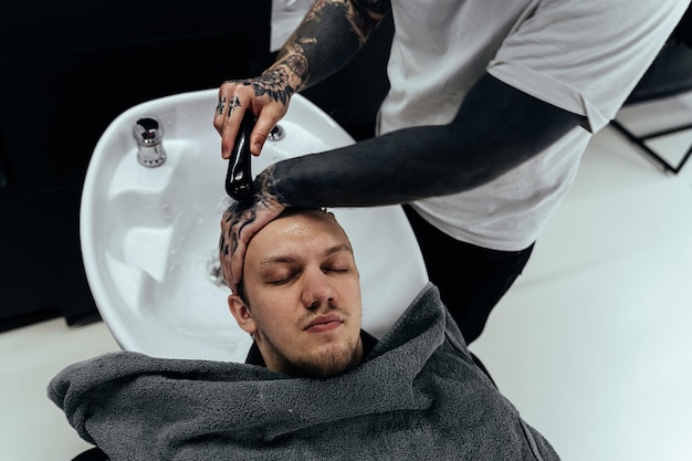 Attractive male is getting a modern haircut in barber shop Top view of a young man getting his hair washed and his head massaged in a hair salon