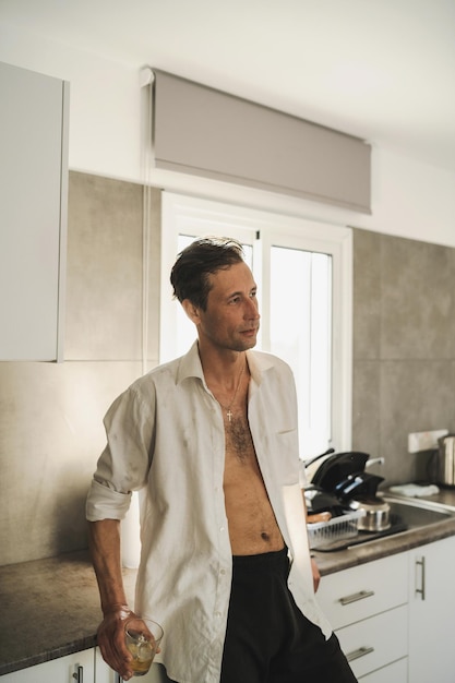 Attractive male slob drinking whiskey in his kitchen