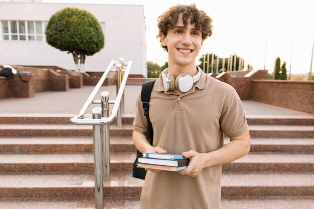 Attractive male student sits on the steps of the university and reads something preparing for exams