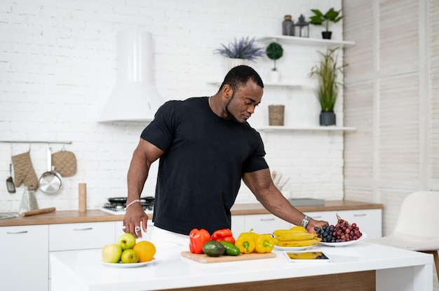 Attractive man cooking vegetarian fruit meal. Handsome young man choosing freah healthy fruits.