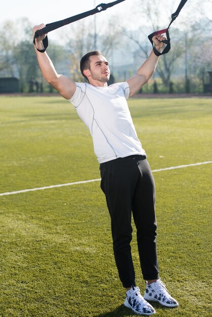 Attractive Man Doing Crossfit With Trx Fitness Straps in City Park Area  Training and Exercising for Endurance  Healthy Lifestyle Concept Outdoor