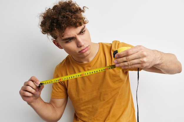 Attractive man measuring tape measure in yellow tshirt light background