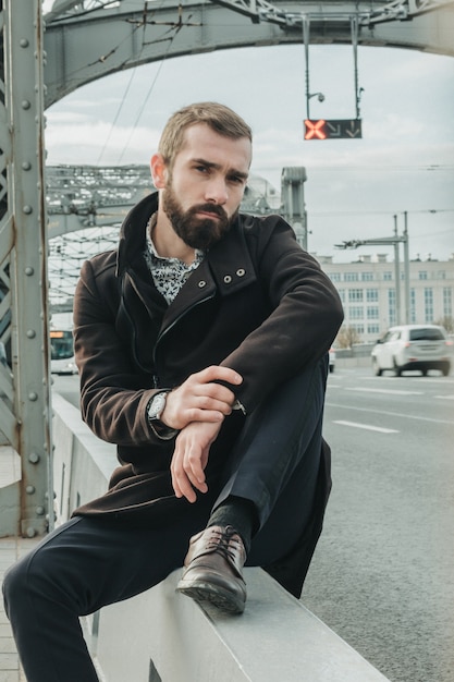 Attractive man near the bridge construction on a cloudy autumn day