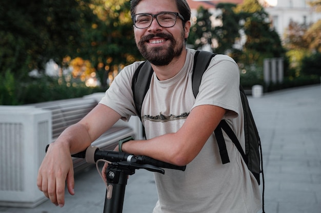 Attractive man riding a kick scooter at cityscape background