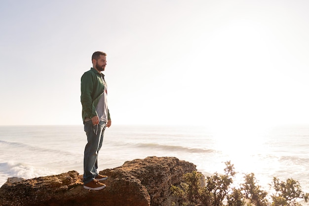 Attractive man standing watching the sunset from a cliff by the sea concept of leisure and relax copy space for text