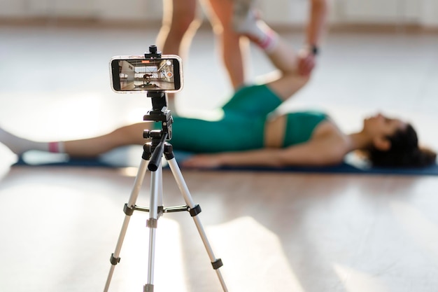 Attractive man stretches woman online training video recording of exercises selective focus