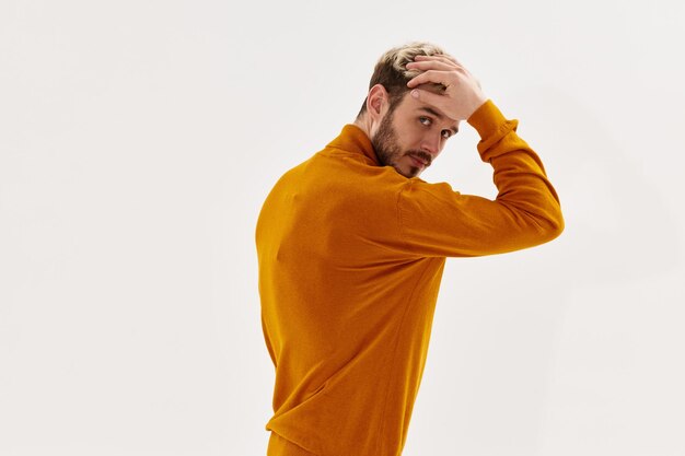 Photo attractive man in a sweater touches his head with his hand and a dark blond beard high quality photo