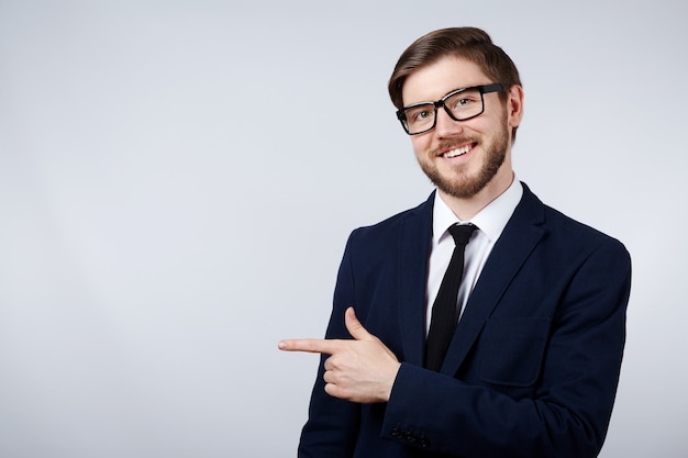 Attractive man wearing suit and glasses  wall, business concept, copy space, pointing on, mock up.