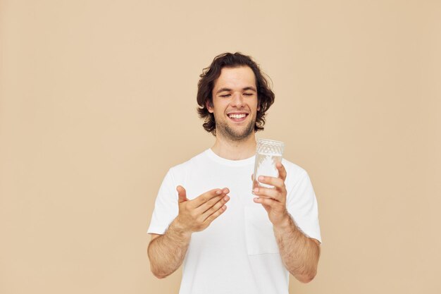 Attractive man in a white tshirt with a mug in hand beige background