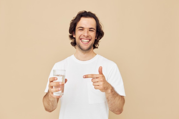 Attractive man in a white tshirt with a mug in hand beige background