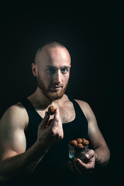 Attractive man with serious face hold walnut nuts.