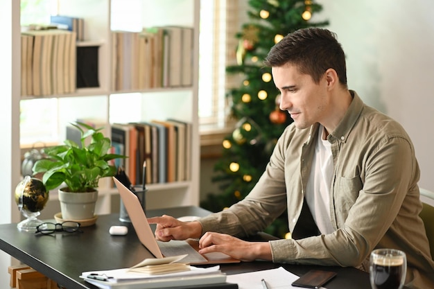 Attractive man working online with laptop computer at home office