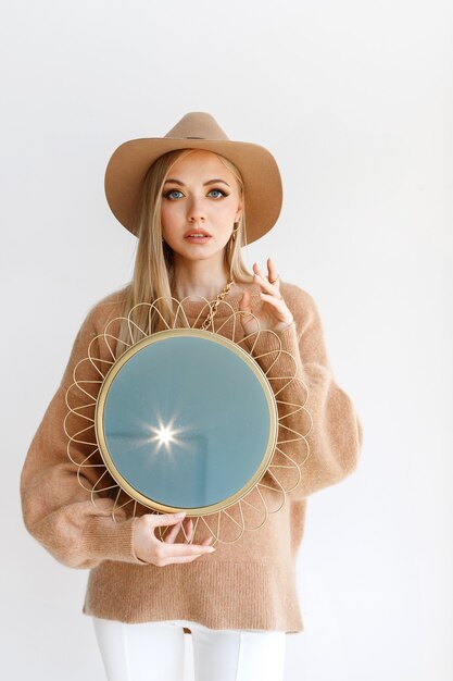 Attractive model with autumn makeup on a light background with a mirror