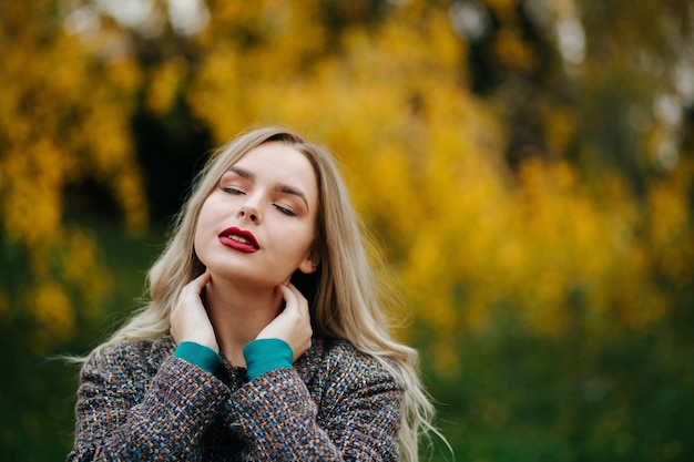 Attractive model with closed eyes posing at the autumn street. Space for text