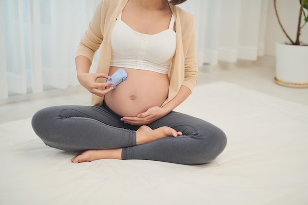 Attractive pregnant woman is lying in bed with toy car on belly It's a boy Last months of pregnancy