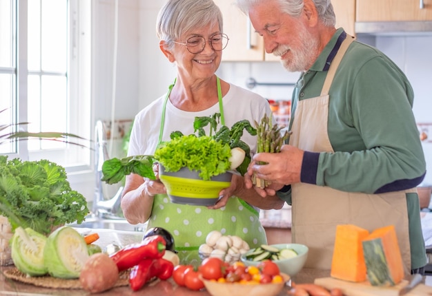 Attractive senior couple preparing vegetables together in the home kitchen Caucasian elderly people enjoying healthy eating